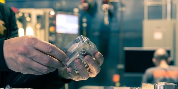 The image shows a man working on a 3D printed metal part  at Autodesk Pier 9 Workshop in San Francisco